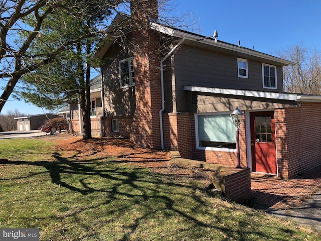 back of house featuring a yard, brick siding, and a chimney