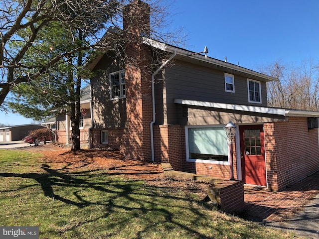 back of house featuring a yard, brick siding, and a chimney