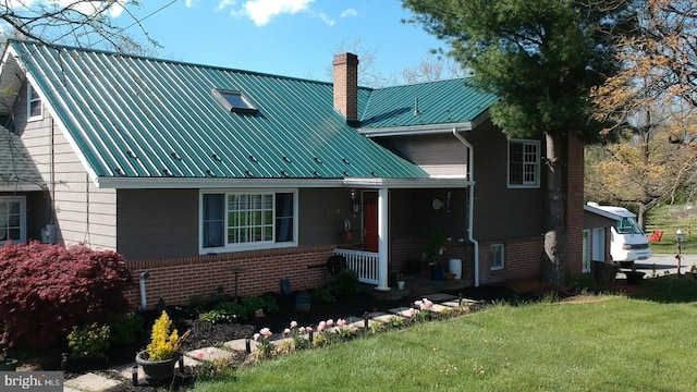 view of front of home featuring metal roof, brick siding, a porch, and a front yard