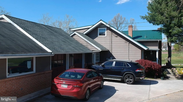 exterior space with brick siding, a chimney, and roof with shingles