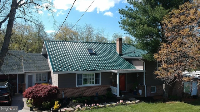 view of front facade with a carport, concrete driveway, metal roof, brick siding, and a chimney