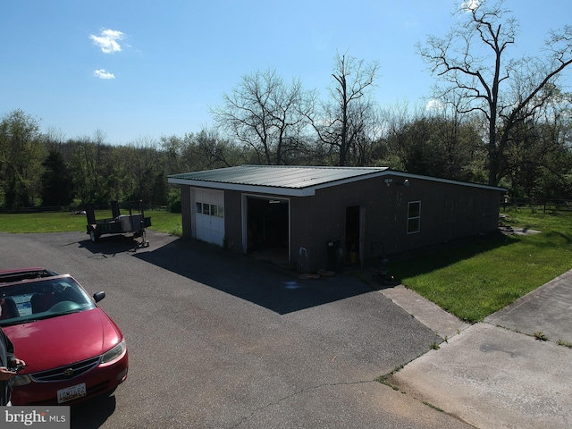 view of front of property with an outdoor structure, metal roof, a garage, and a front yard