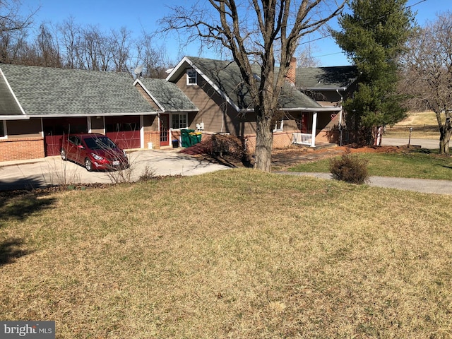 view of front of house with roof with shingles, concrete driveway, a front yard, a carport, and brick siding