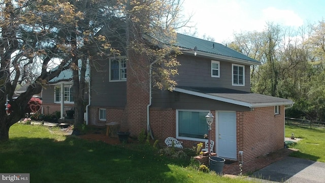 rear view of house featuring a yard and brick siding