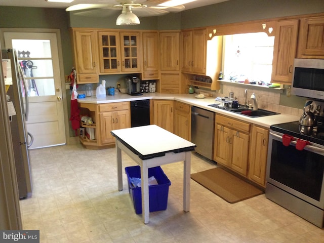 kitchen with tasteful backsplash, light floors, appliances with stainless steel finishes, a ceiling fan, and a sink