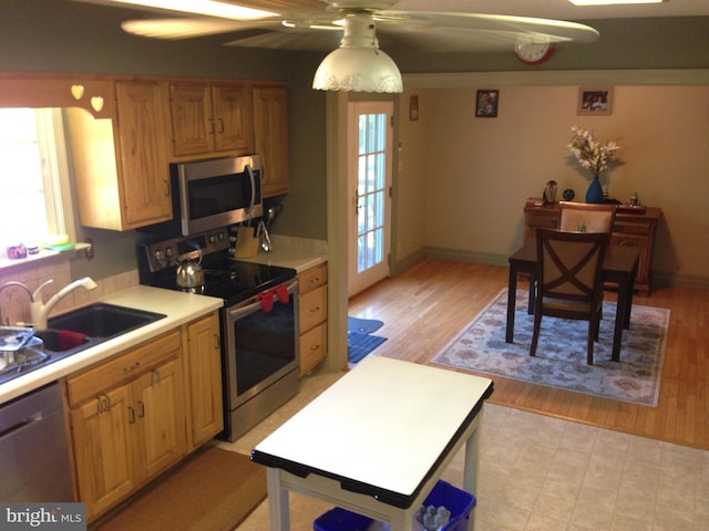 kitchen featuring light wood finished floors, light countertops, stainless steel appliances, a ceiling fan, and a sink