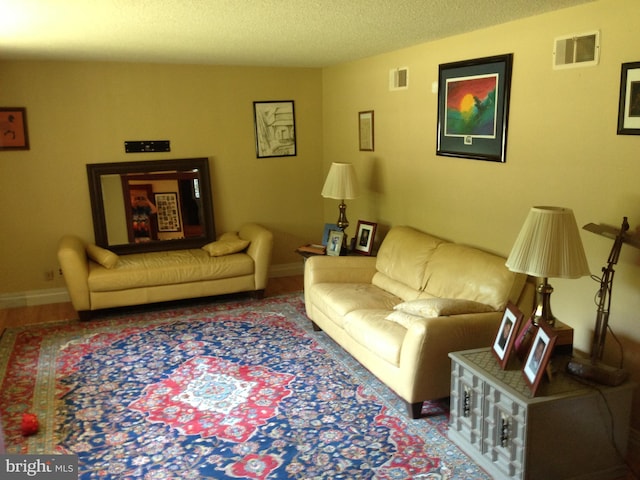 living room featuring visible vents, a textured ceiling, and baseboards