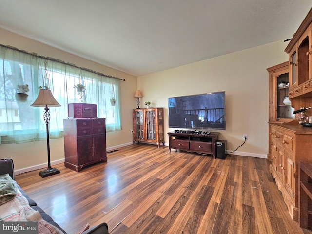 living room with visible vents, baseboards, and wood finished floors