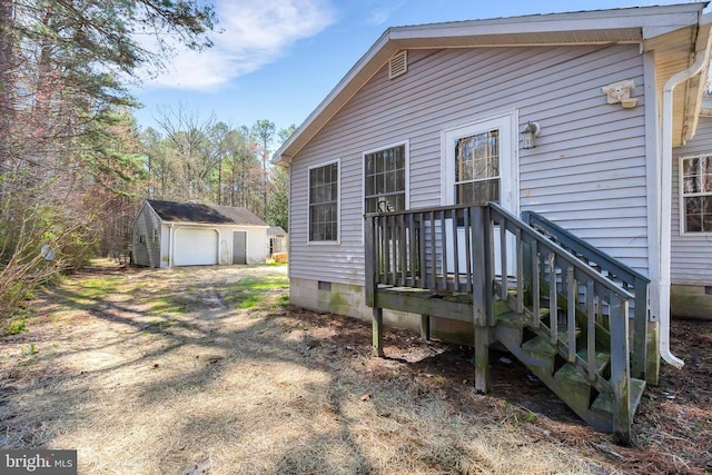 rear view of property with an outdoor structure, driveway, crawl space, and a garage