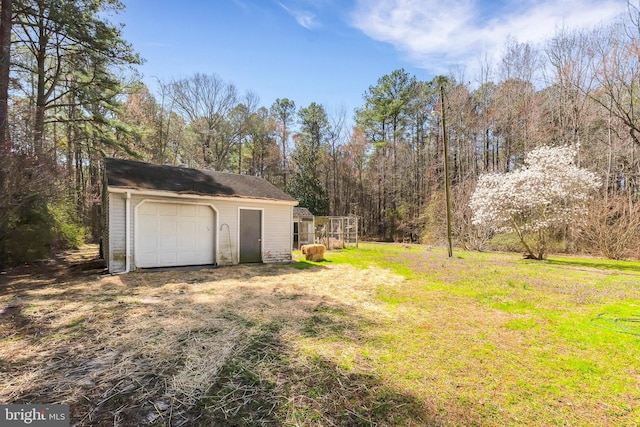 view of yard with an outdoor structure, a wooded view, and a garage