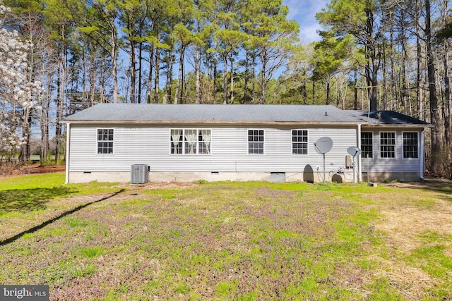 back of property with a lawn, central air condition unit, and crawl space