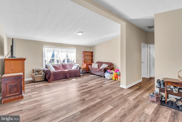 living area with baseboards, light wood-style floors, and a textured ceiling