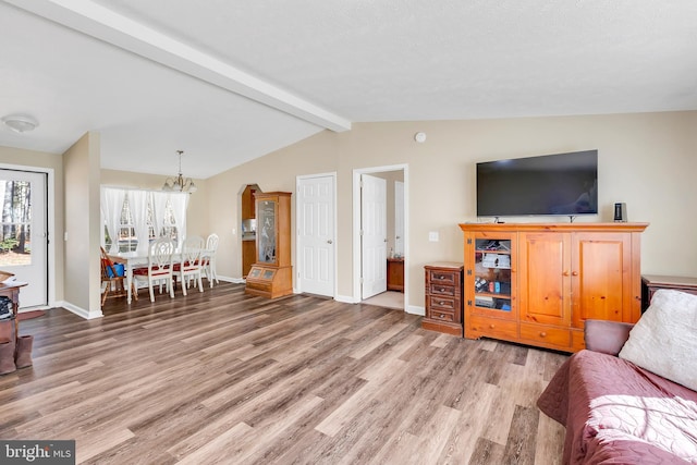 living room with baseboards, lofted ceiling with beams, wood finished floors, and an inviting chandelier