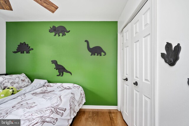 bedroom featuring a closet, an accent wall, baseboards, and wood finished floors