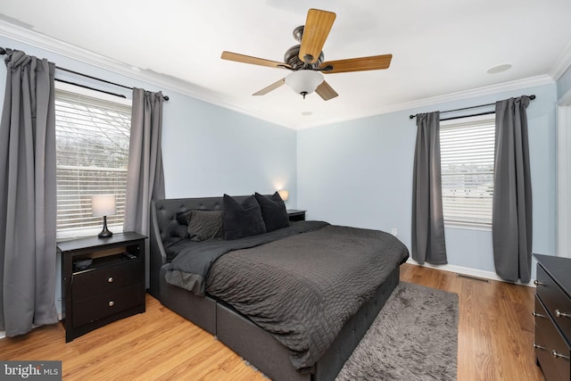 bedroom with visible vents, light wood-style floors, crown molding, and a ceiling fan