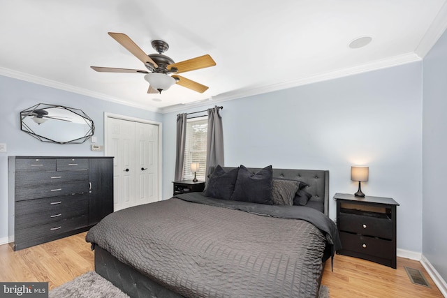 bedroom with light wood-type flooring, visible vents, baseboards, and crown molding