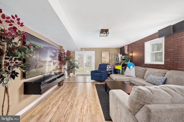 living room featuring an accent wall, french doors, wood finished floors, and brick wall