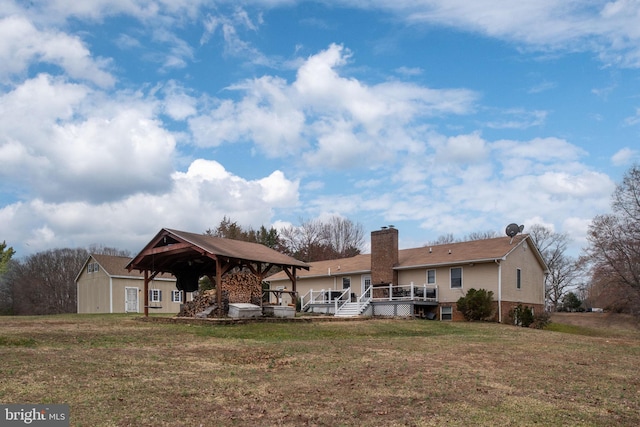 back of property with a gazebo, a lawn, a chimney, an outdoor structure, and a deck