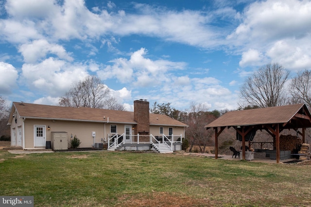 back of property with central air condition unit, a wooden deck, a gazebo, a chimney, and a yard