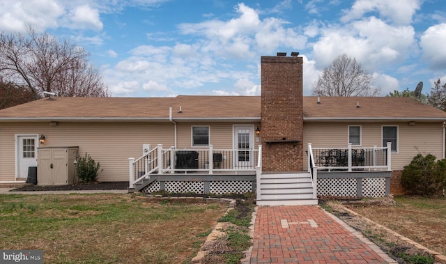 back of house featuring a wooden deck, a lawn, and a chimney