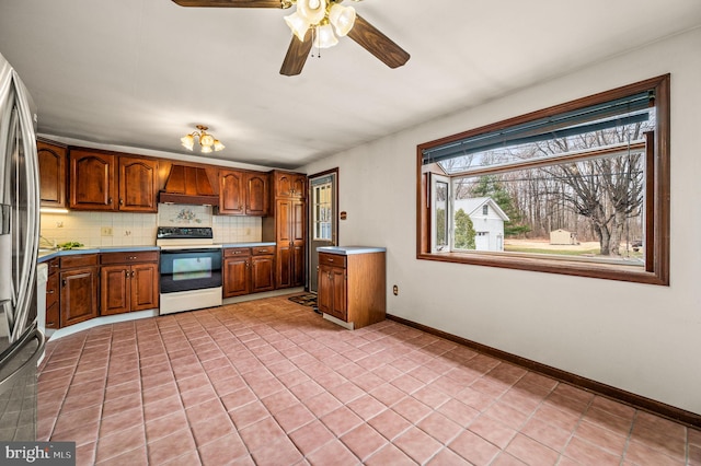 kitchen featuring custom exhaust hood, electric range, brown cabinetry, and backsplash