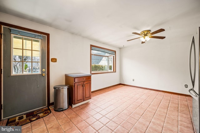 interior space featuring light tile patterned floors, a ceiling fan, and baseboards