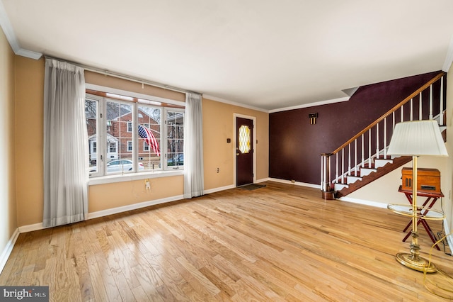 entrance foyer with baseboards, wood-type flooring, ornamental molding, and stairway