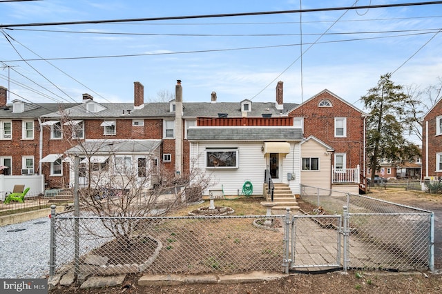 view of property featuring a shingled roof, a gate, a fenced front yard, and a chimney