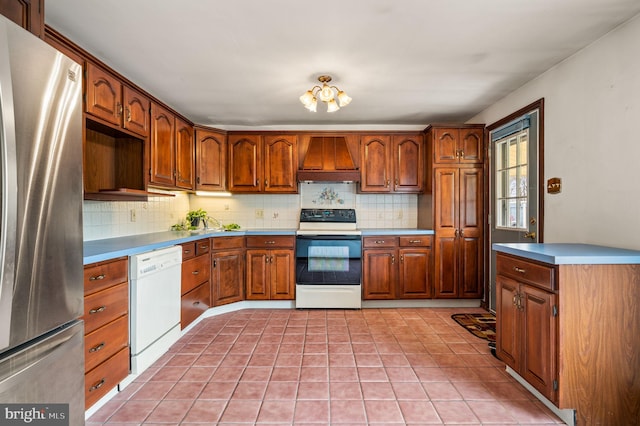 kitchen with premium range hood, freestanding refrigerator, range with electric cooktop, dishwasher, and backsplash