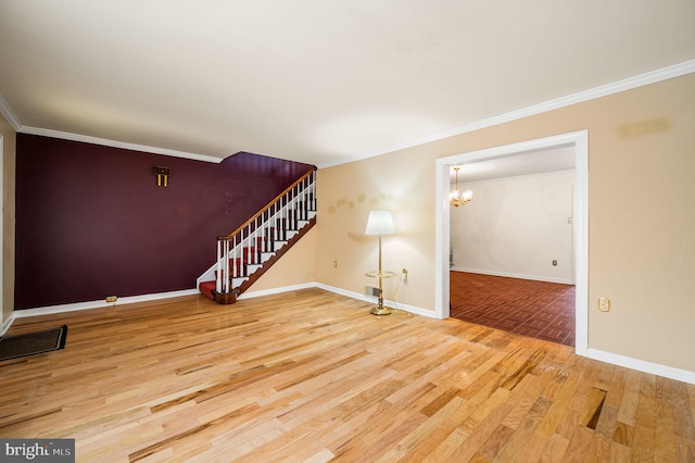 unfurnished living room with crown molding, baseboards, a chandelier, stairway, and wood finished floors