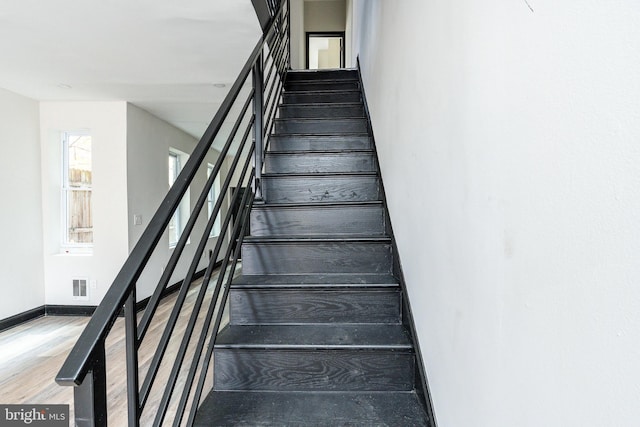 stairway featuring wood finished floors, visible vents, and baseboards