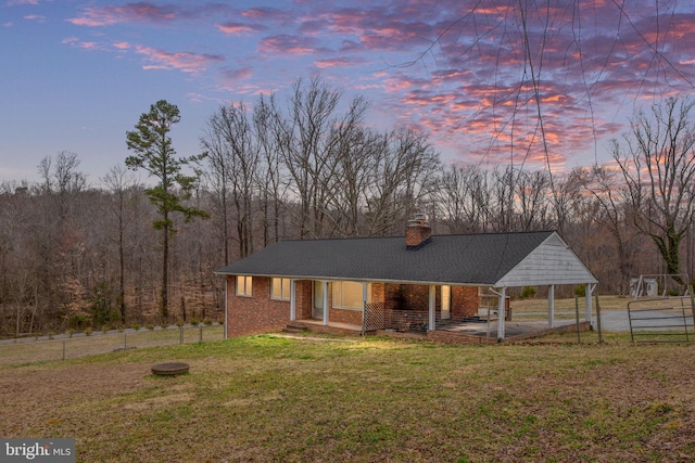 view of front of home with a front lawn, fence, a chimney, and a carport