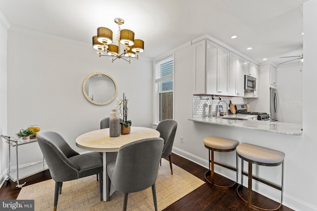 dining space with crown molding, baseboards, dark wood finished floors, recessed lighting, and an inviting chandelier