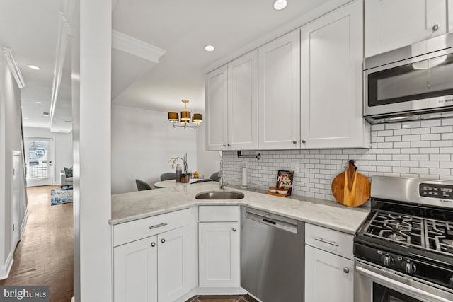 kitchen with a sink, light stone counters, appliances with stainless steel finishes, white cabinets, and decorative backsplash