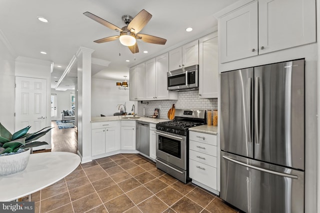 kitchen featuring backsplash, stainless steel appliances, crown molding, light countertops, and ceiling fan