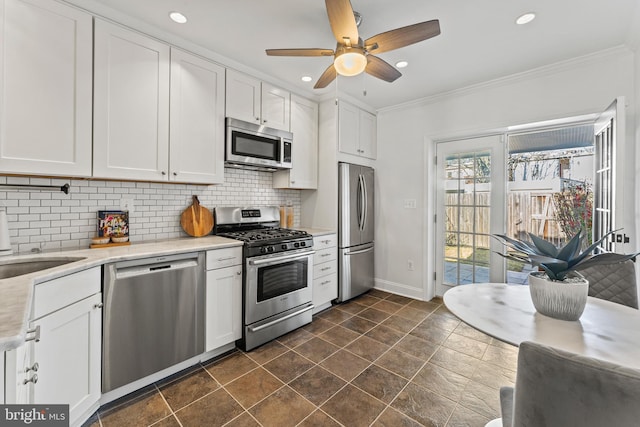 kitchen with decorative backsplash, white cabinetry, stainless steel appliances, and crown molding