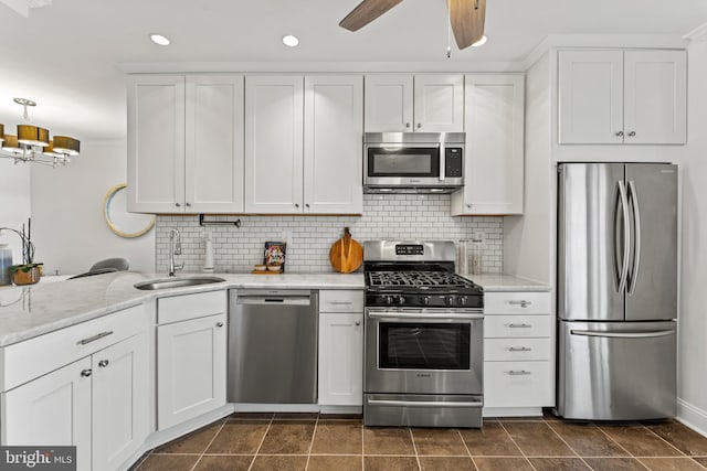 kitchen featuring tasteful backsplash, white cabinetry, stainless steel appliances, and a sink