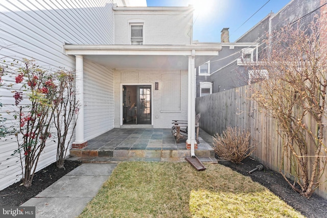 property entrance featuring fence and brick siding