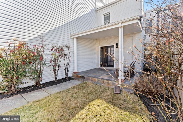 doorway to property with a lawn and brick siding