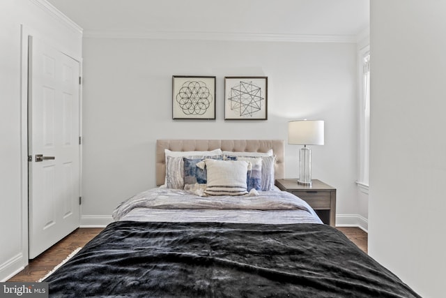 bedroom with ornamental molding, baseboards, and wood finished floors