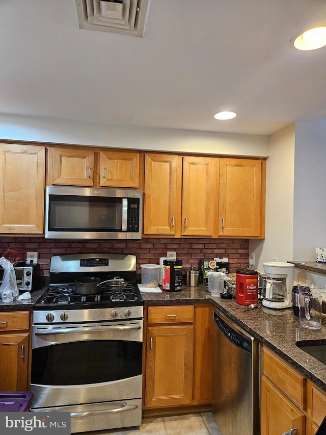 kitchen featuring dark stone countertops, backsplash, visible vents, and appliances with stainless steel finishes