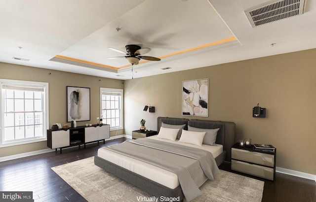 bedroom featuring visible vents, baseboards, dark wood-type flooring, and a tray ceiling