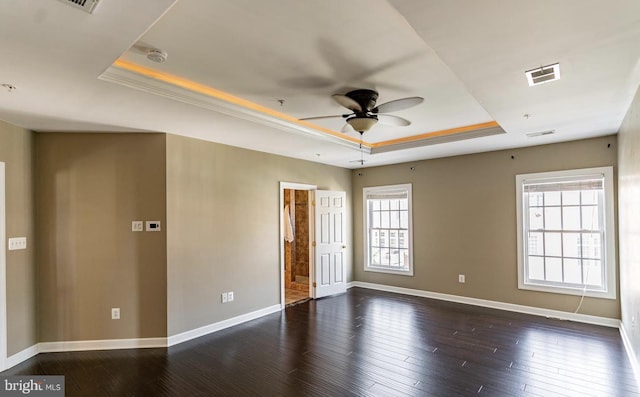 spare room with dark wood finished floors, a healthy amount of sunlight, a raised ceiling, and ceiling fan