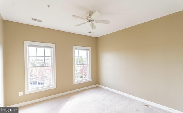 spare room with a ceiling fan, baseboards, visible vents, and light carpet