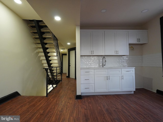 kitchen featuring backsplash, dark wood-type flooring, light countertops, white cabinets, and a sink