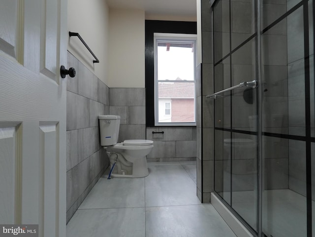 full bath with toilet, tile walls, a stall shower, and tile patterned flooring