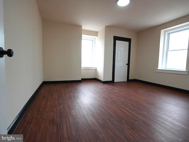 empty room with dark wood-style floors and baseboards