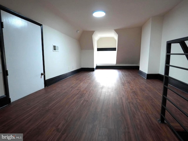 bonus room featuring dark wood-style floors, visible vents, baseboards, and lofted ceiling