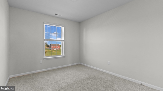 carpeted spare room with visible vents and baseboards