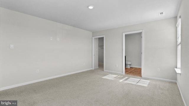 unfurnished bedroom with a spacious closet, visible vents, carpet flooring, and baseboards